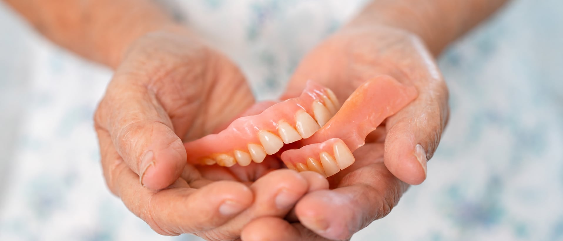 Patient holding a set of dentures in her hands