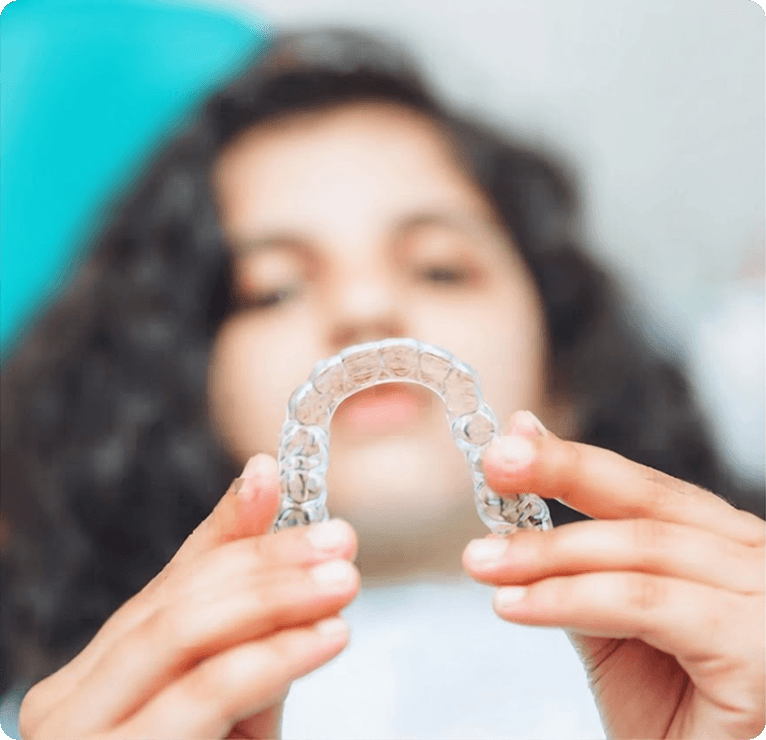 Patient smiling while holding clear aligners