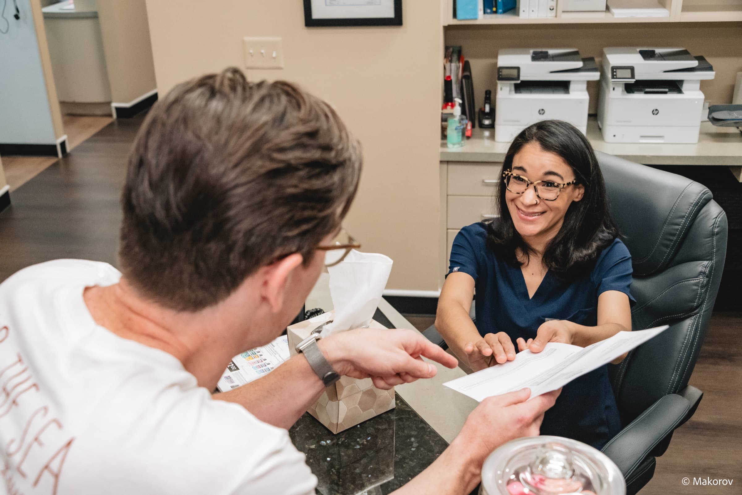 Landmark Smiles team member reviewing paperwork with a patient at the front desk