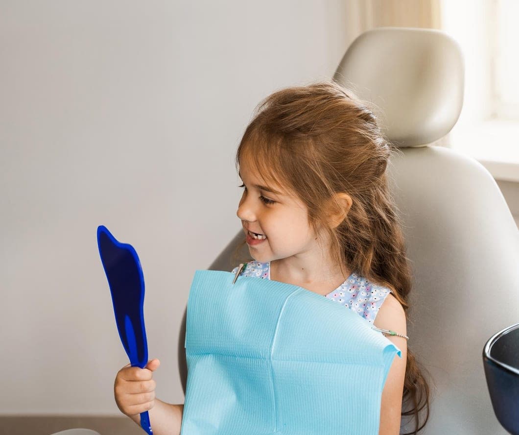 Young girl checking her smile in a hand mirror