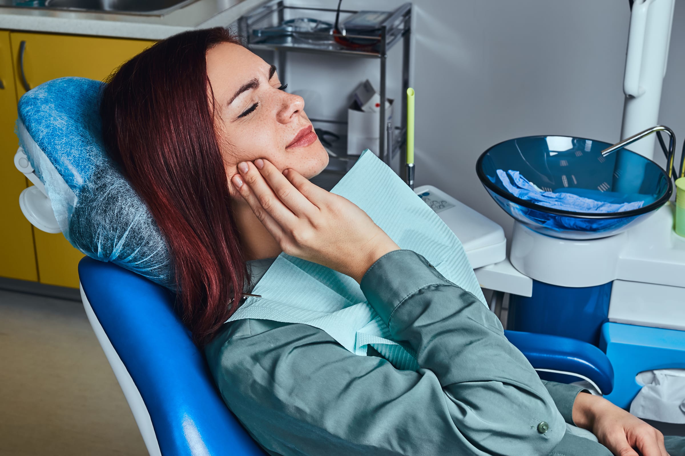 Patient holding her cheek in the dental chair
